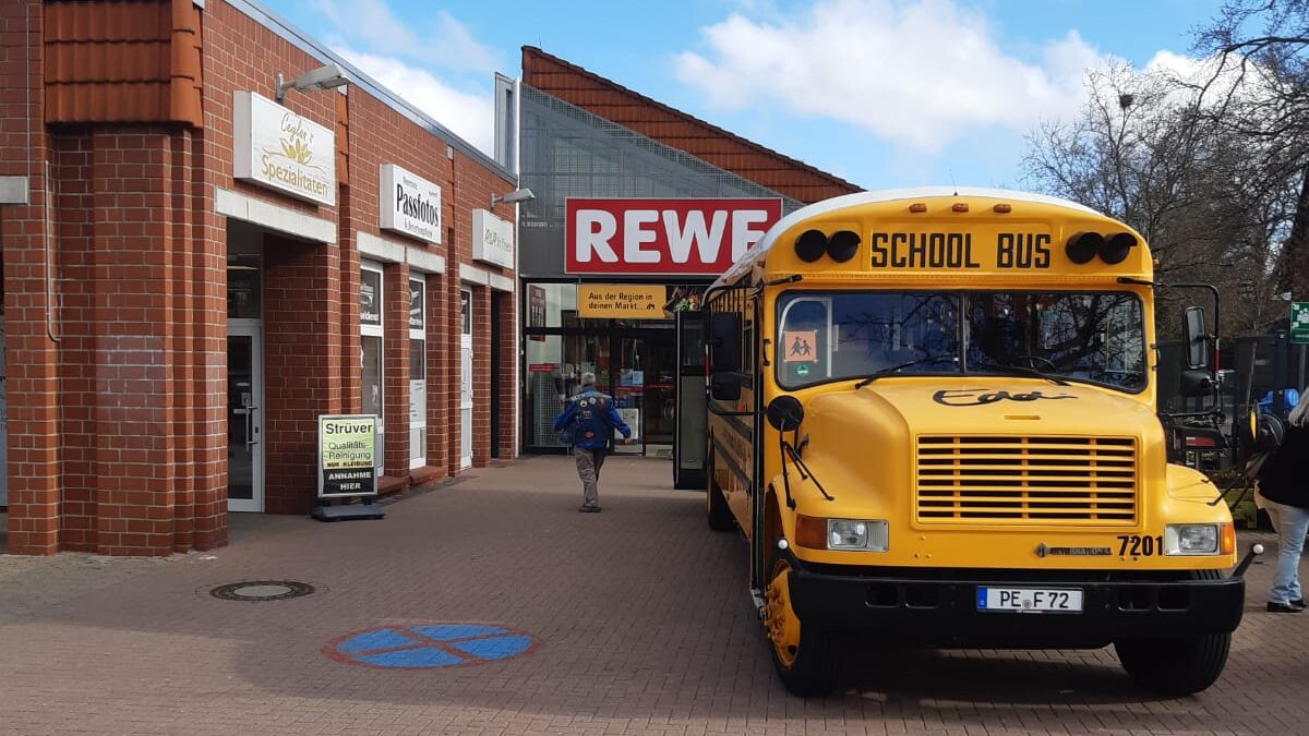 US-Schoolbus vor einer Rewe-Filiale